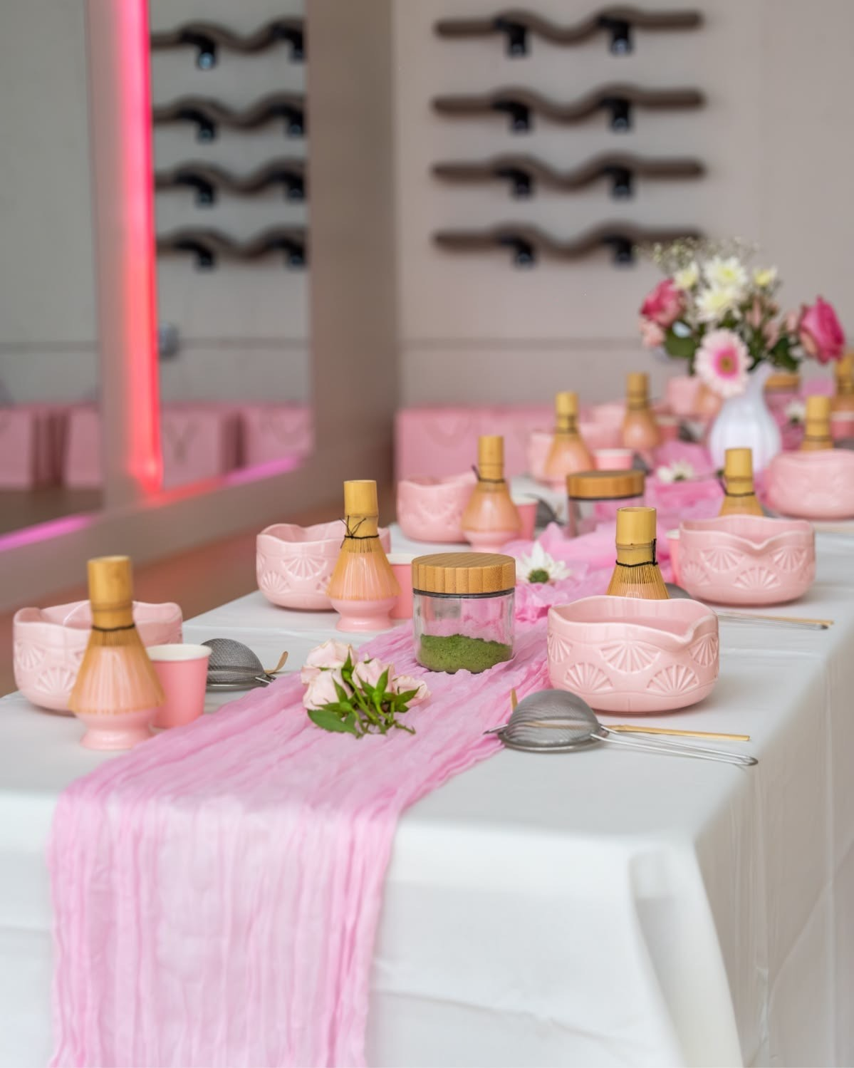 A beautifully styled wellness event table with pink matcha bowls, whisks, and florals
